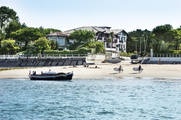 A beach with a boat, people, and a building with a balcony.