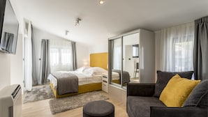 Ein modernes Schlafzimmer mit einem Bett, einer Couch, einem Spiegel und einem Kleiderschrank.