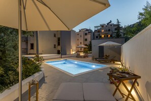 Poolområde på taget med liggestol, parasol og et bord med mad.