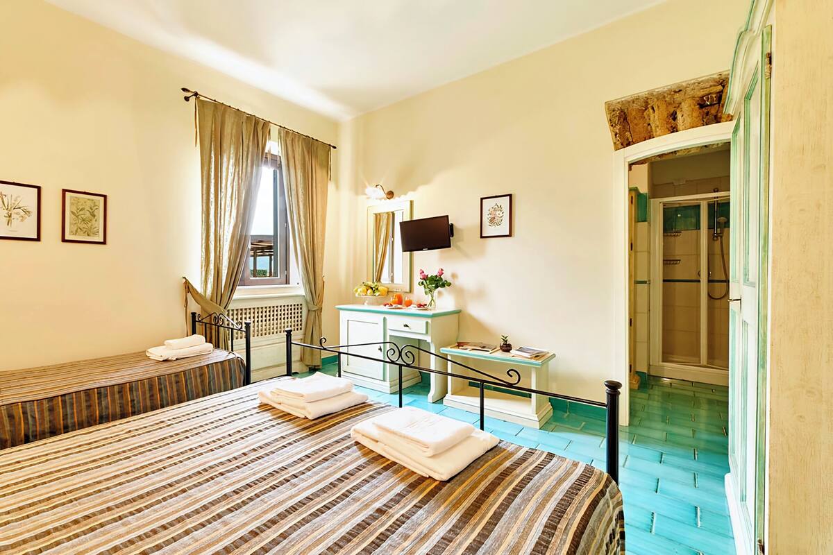 Habitación de hotel con dos camas, baño y una mesita con espejo.