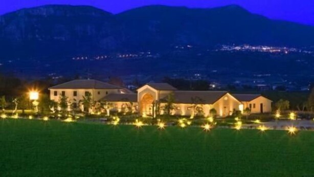 Un hotel con varias construcciones, un césped bien iluminado y un telón de fondo montañoso.