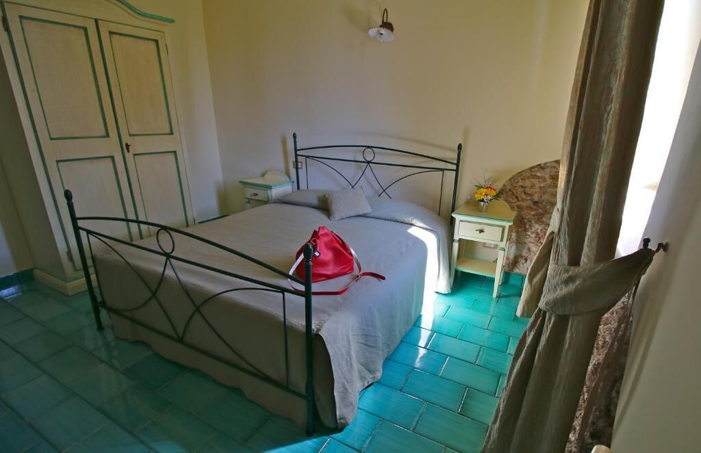 A bedroom with a bed, a nightstand, a dresser, and a door.