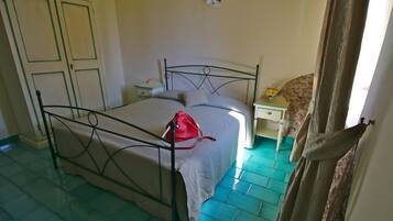 A bedroom with a bed, a nightstand, a dresser, and a door.
