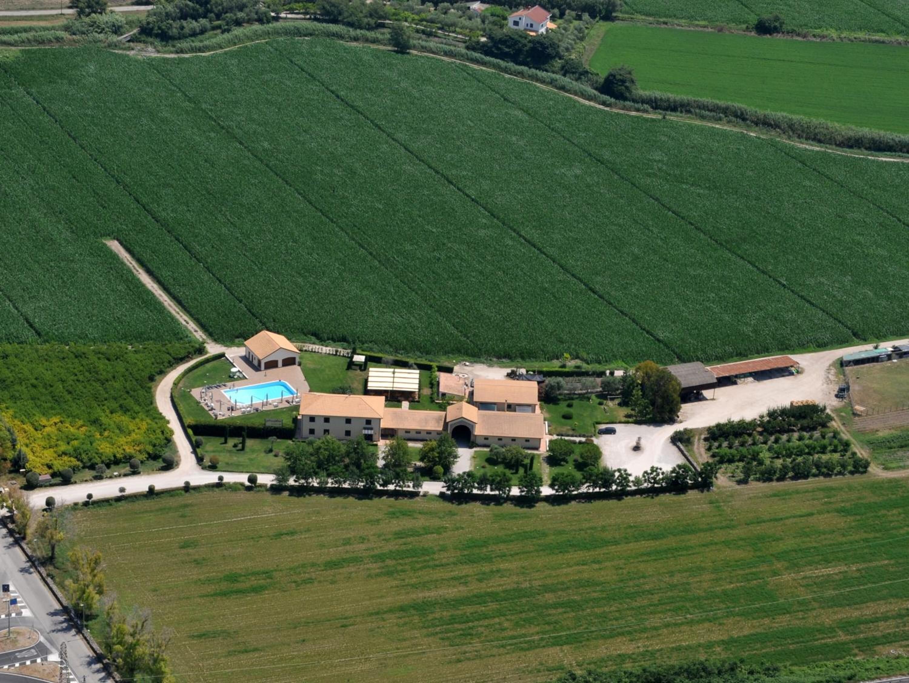 An aerial view of a large estate with multiple buildings, including a main house, guesthouses, and a swimming pool.