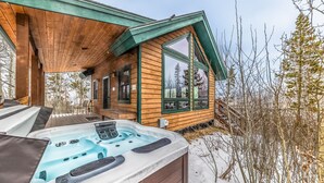 En træhytte med jacuzzi og terrasse.