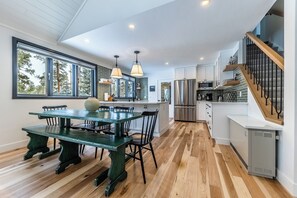 A modern kitchen with a dining area, wooden flooring, and a staircase.
