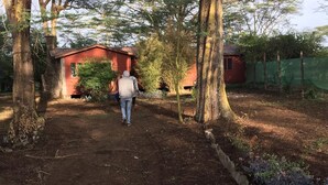 A dirt path leading to a red building surrounded by trees. - Kikopey Beach Camp (Gilgil)