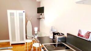 A compact kitchenette with a stove, toaster, and fan. - White's Row Resident (London)
