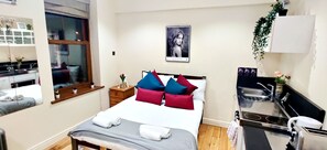 Une chambre d’hôtel avec un lit, une table de chevet et une petite fenêtre.