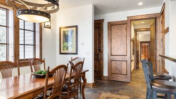 A dining area with a wooden table and chairs, a chandelier, and a framed picture on the wall.