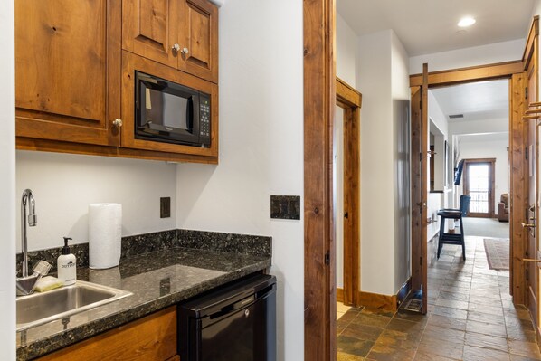 A kitchen with wooden cabinets, a granite countertop, a built-in microwave, and a dishwasher.