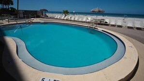 A swimming pool with a view of the ocean and a beach area with lounge chairs. - Sand Castle III Luxury Condo, Free nights for select dates. (Indian Shores)
