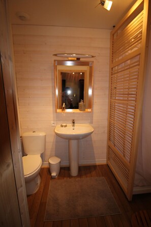 Un baño con paredes de madera, un lavamanos, un inodoro y un espejo.