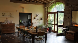 Un comedor con una mesa y sillas de madera, una planta en maceta y vistas por un amplio ventanal.