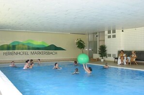 Ein Hallenbad, in dem Menschen schwimmen und mit einem Ball spielen.