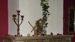 Una chimenea con fuego, un candelabro y un florero con flores sobre la repisa.