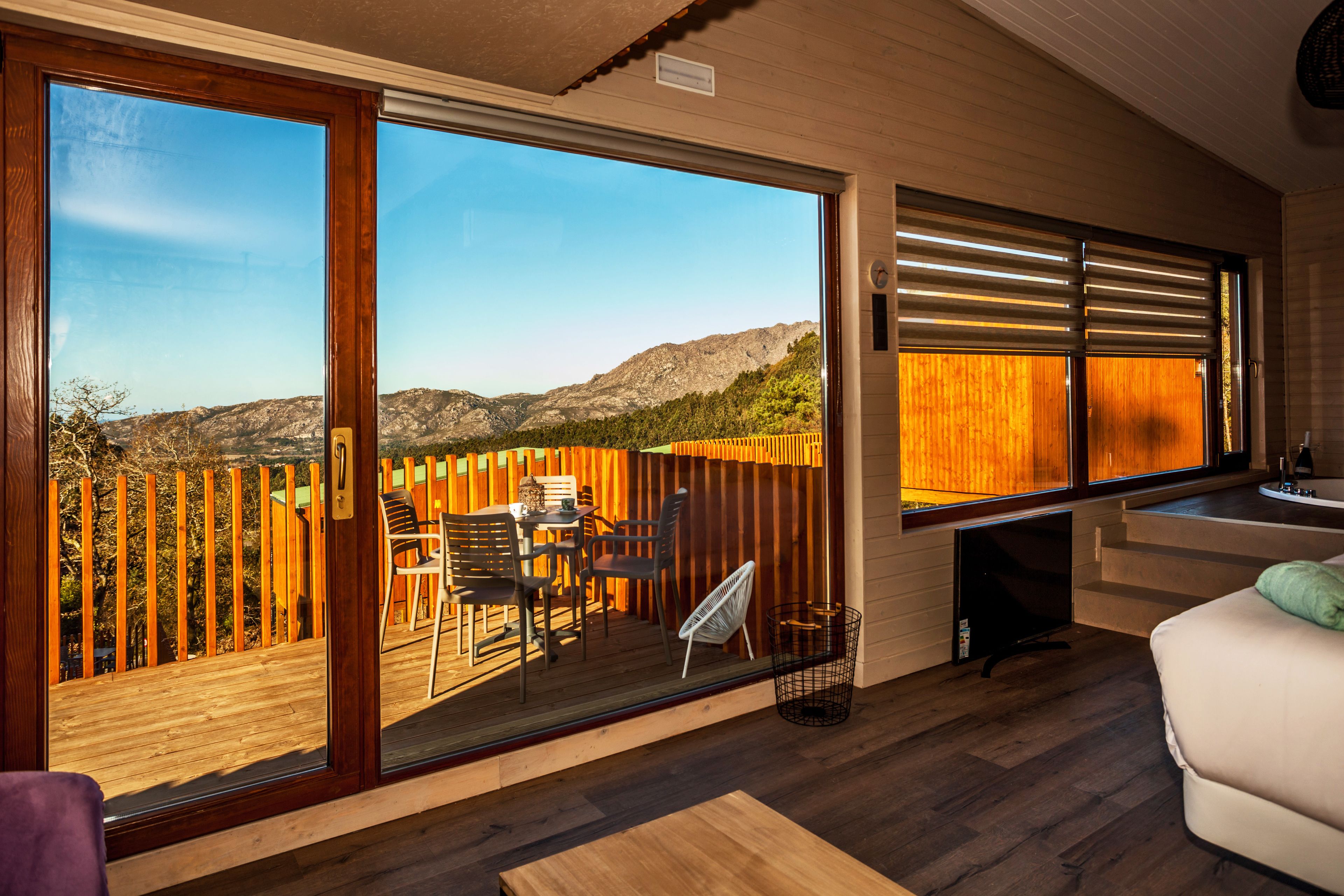 A room with a large sliding glass door leading to an outdoor deck with a wooden fence and chairs.