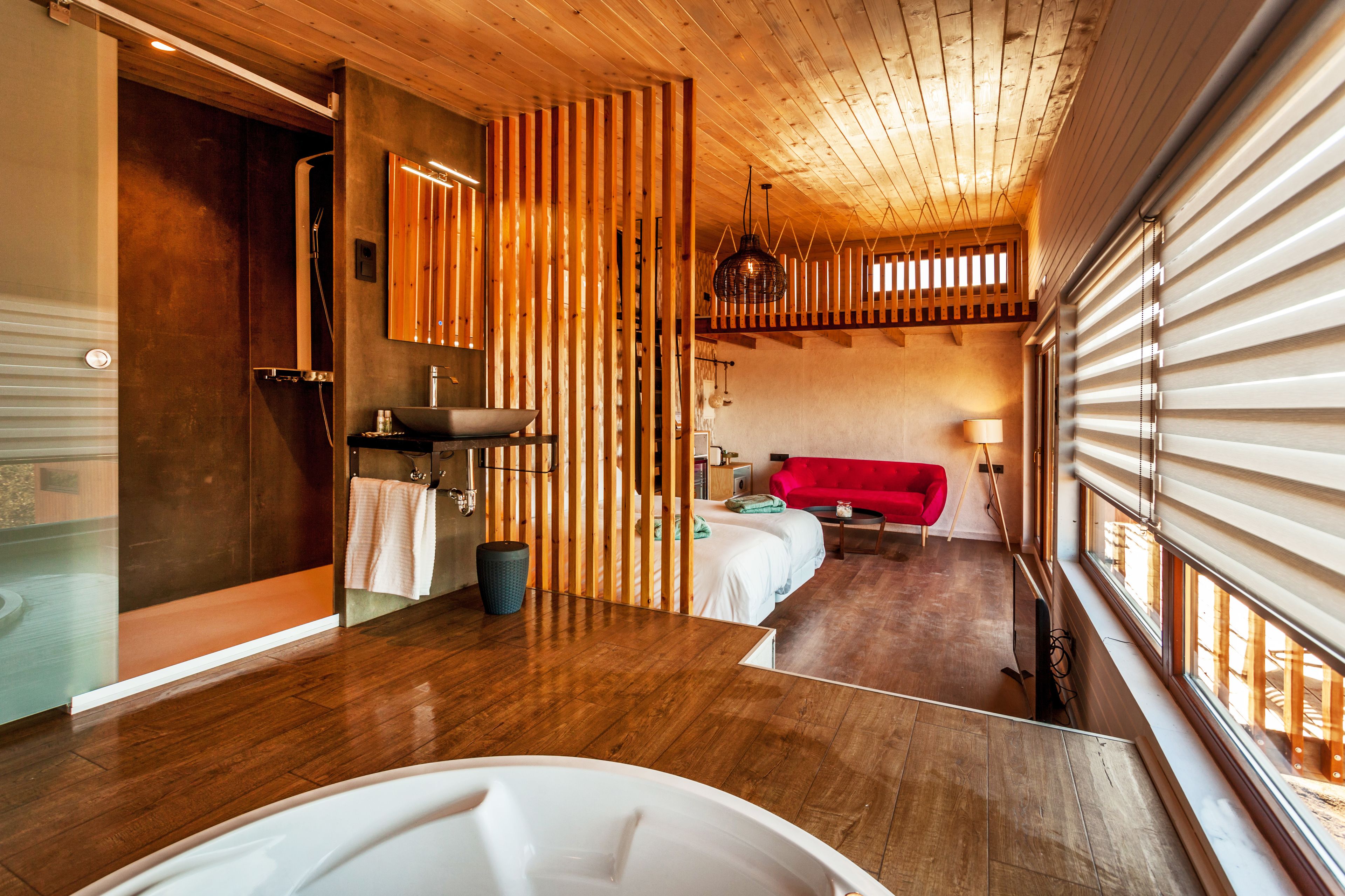 A modern bathroom with a wooden floor, a bathtub, and a shower area.