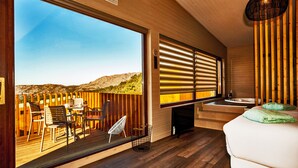 A modern room with a large sliding glass door leading to an outdoor deck, a wooden floor, a bed with green pillows, and a built-in TV. - Nidos de Carnota (Carnota)