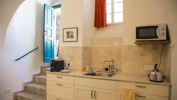A compact kitchen with a sink, a microwave, and a kettle on the counter.