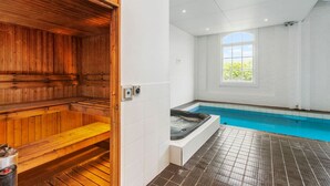 A sauna with wooden benches and a separate hot tub area with a tiled floor and a window. - Sunlit City Fringe Apartment wth Heat Pump+Carpark (Auckland)