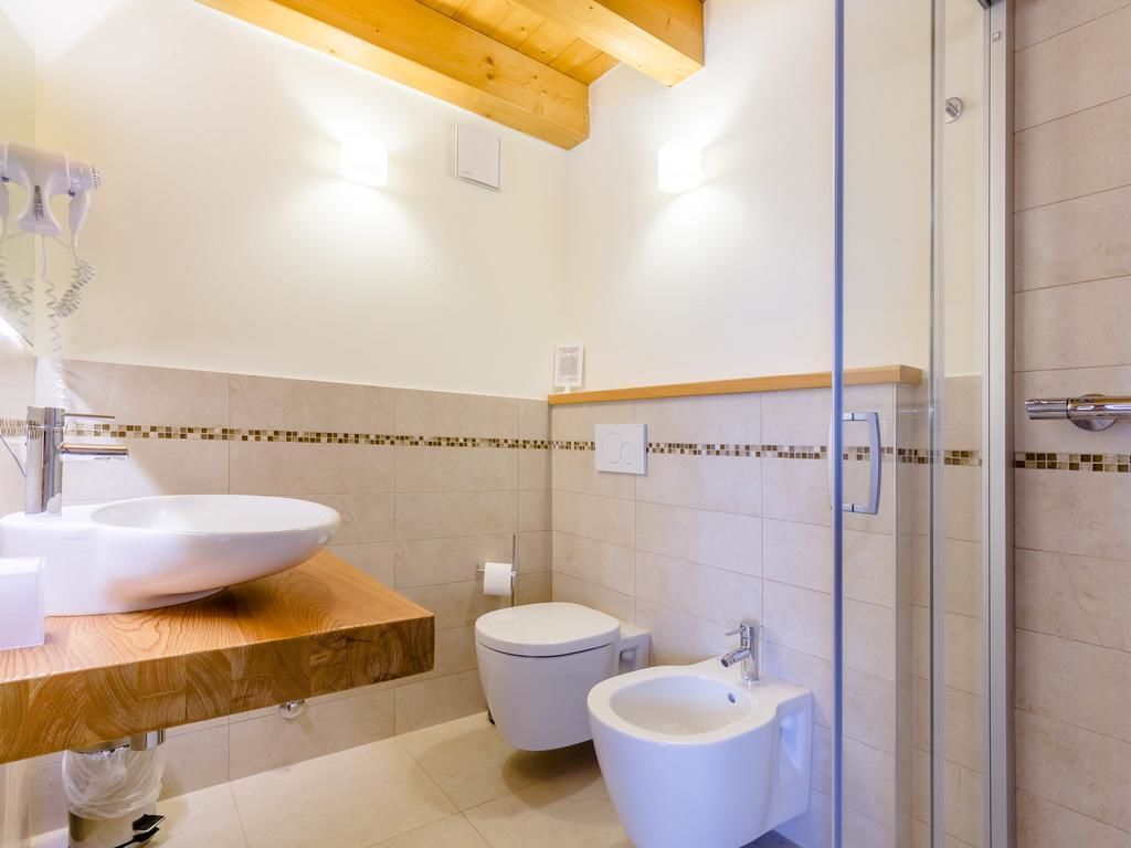 A modern bathroom with a wooden vanity, a large sink, a bidet, and a glass shower enclosure.