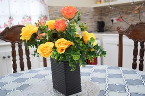 A black vase with yellow and orange flowers on a table with a blue and white patterned tablecloth. - Justinn Apartments (Gros Islet)