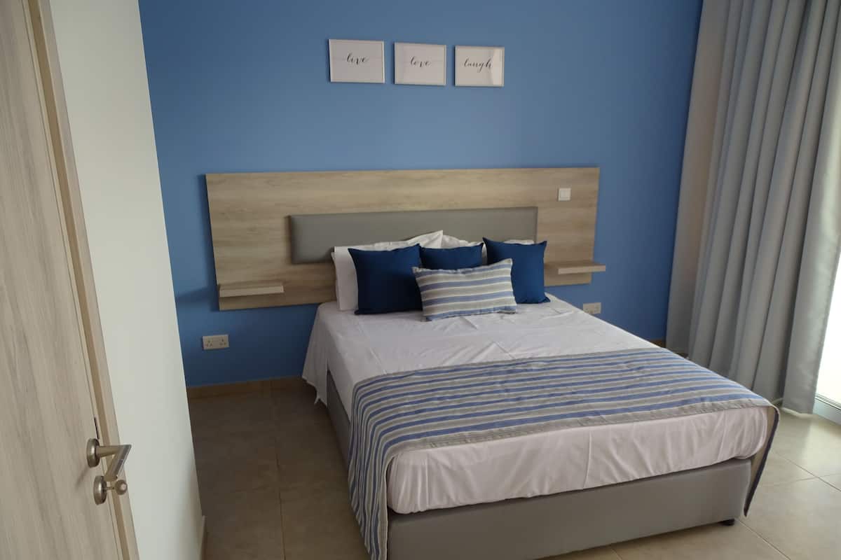 A bedroom with a bed, a headboard, and three framed signs on the wall.