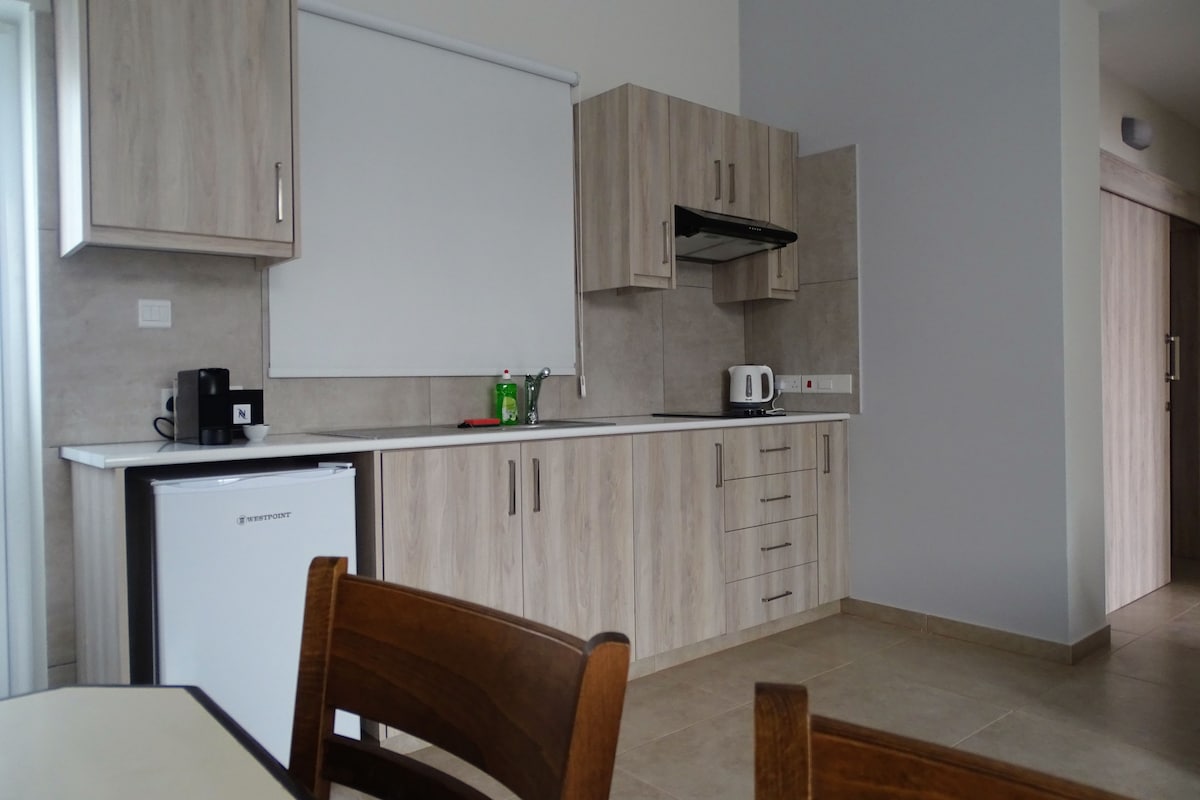A compact kitchen with wooden cabinets, a built-in microwave, and a coffee maker on the counter.