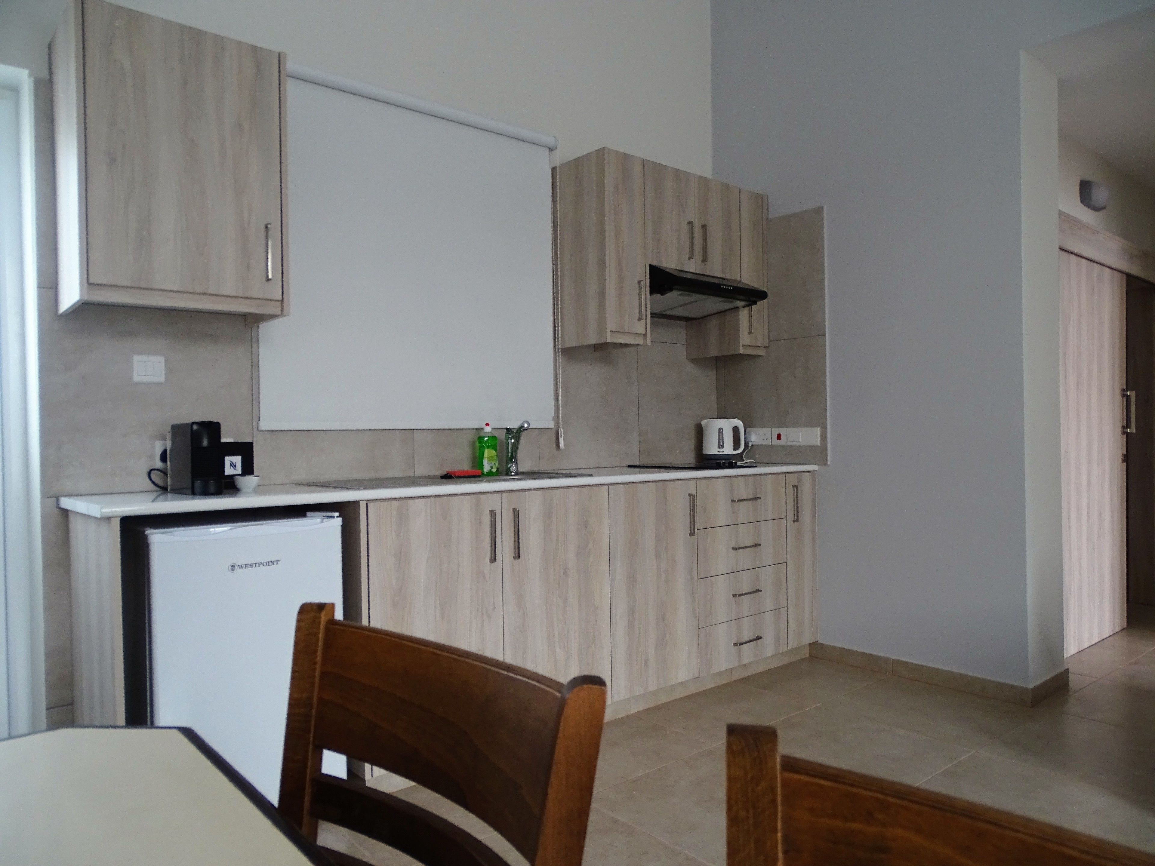 A compact kitchen with wooden cabinets, a built-in microwave, and a coffee maker on the counter.