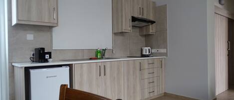 A compact kitchen with wooden cabinets, a built-in microwave, and a coffee maker on the counter.