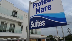 A sign for "Proteas Suites" in front of a modern building with balconies. - Proteas Mare Suites (Paralimni)