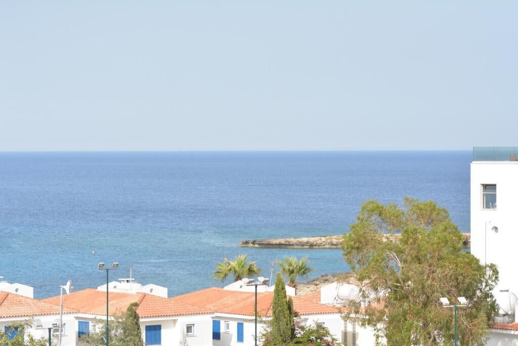 Vista costera con edificios blancos, techos rojos y un mar azul claro.
