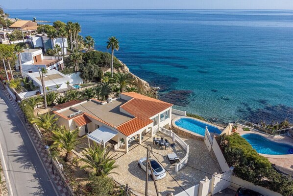 A coastal property with a swimming pool, a car, and a view of the sea. - Luxury villa with its own swimming pool, directly by the sea, stairs to the see. (El Campello)