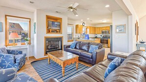 Ein großzügiges Wohnzimmer mit Kamin, Ledersofas und einem Essbereich mit Holzschränken, im Hintergrund eine Küche.