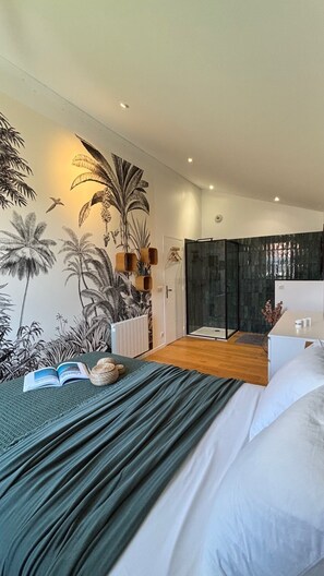 A modern bedroom with a large bed, a shower area, and a tropical-themed wall mural. - Villa in the Biarritz Hills: Heated pool, garden, terrace, parking (Biarritz)