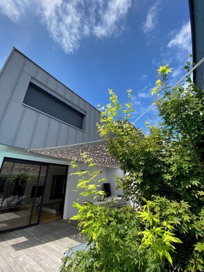 A modern building with a large window and a covered patio area. - Villa in the Biarritz Hills: Heated pool, garden, terrace, parking (Biarritz)
