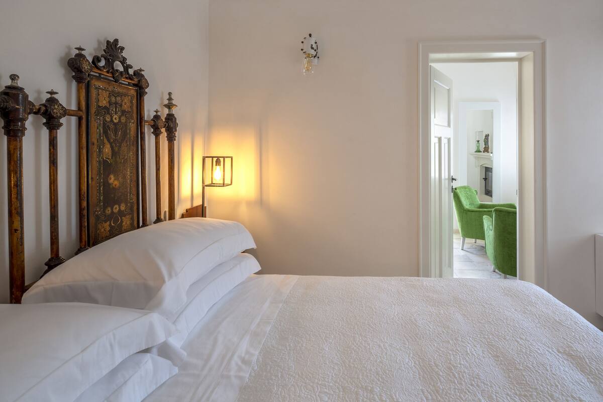 A neatly made bed with white linens and a decorative headboard.