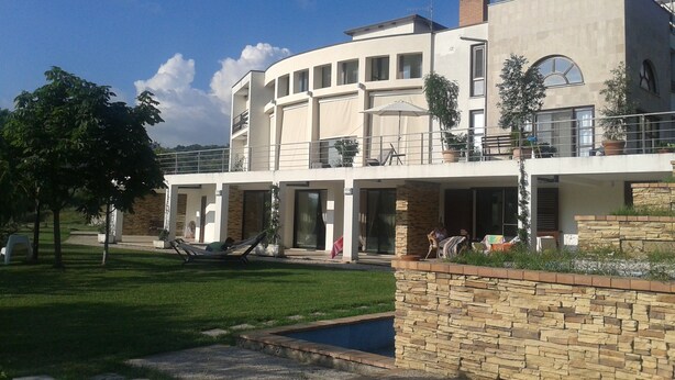 Una casa moderna de dos pisos con piscina, muro de piedra y césped.
