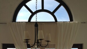 Un comedor con una mesa para dos, una araña y vistas a través de amplios ventanales.