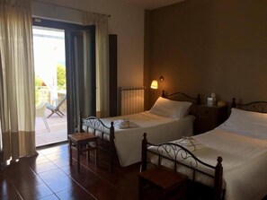Une chambre d’hôtel avec deux lits, une petite table, une chaise et une vue sur l’extérieur.
