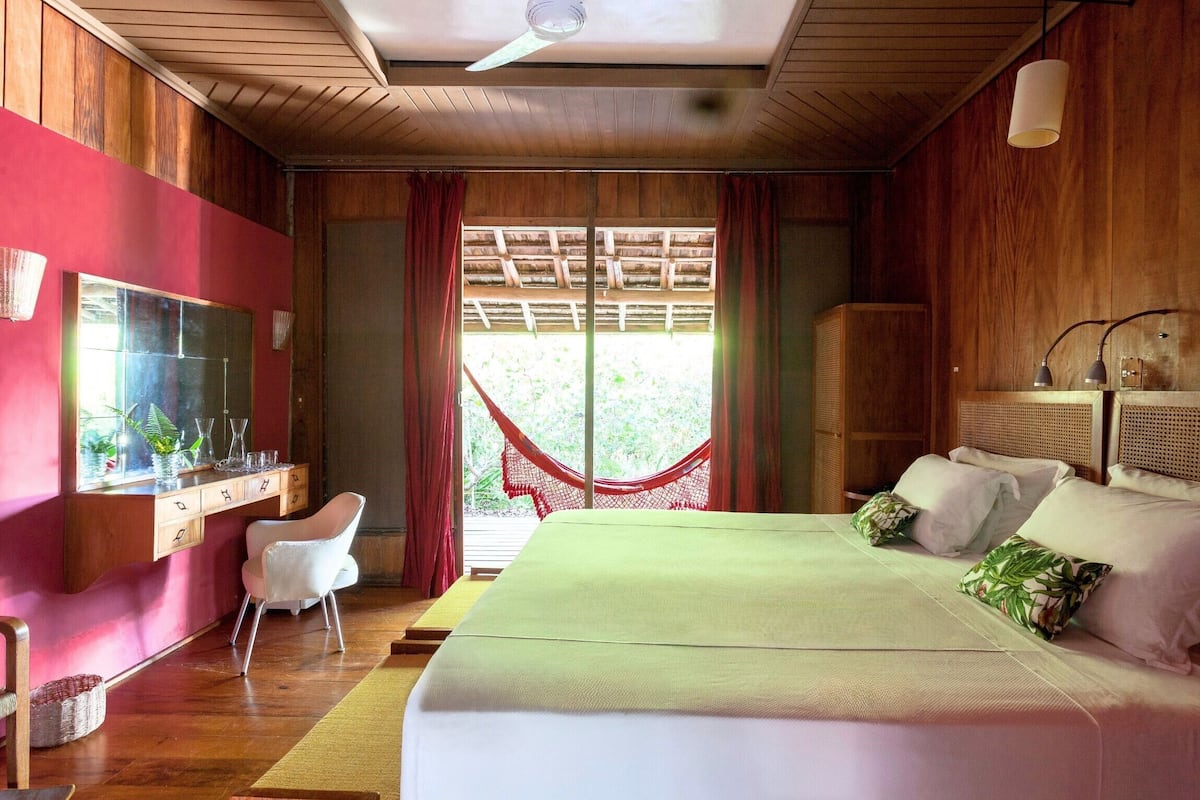 A bedroom with a bed, a desk, a chair, and a hammock.