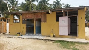 A small, single-story building with a yellow exterior and wooden signage. - Cabins in Aguja Island (Narganá)