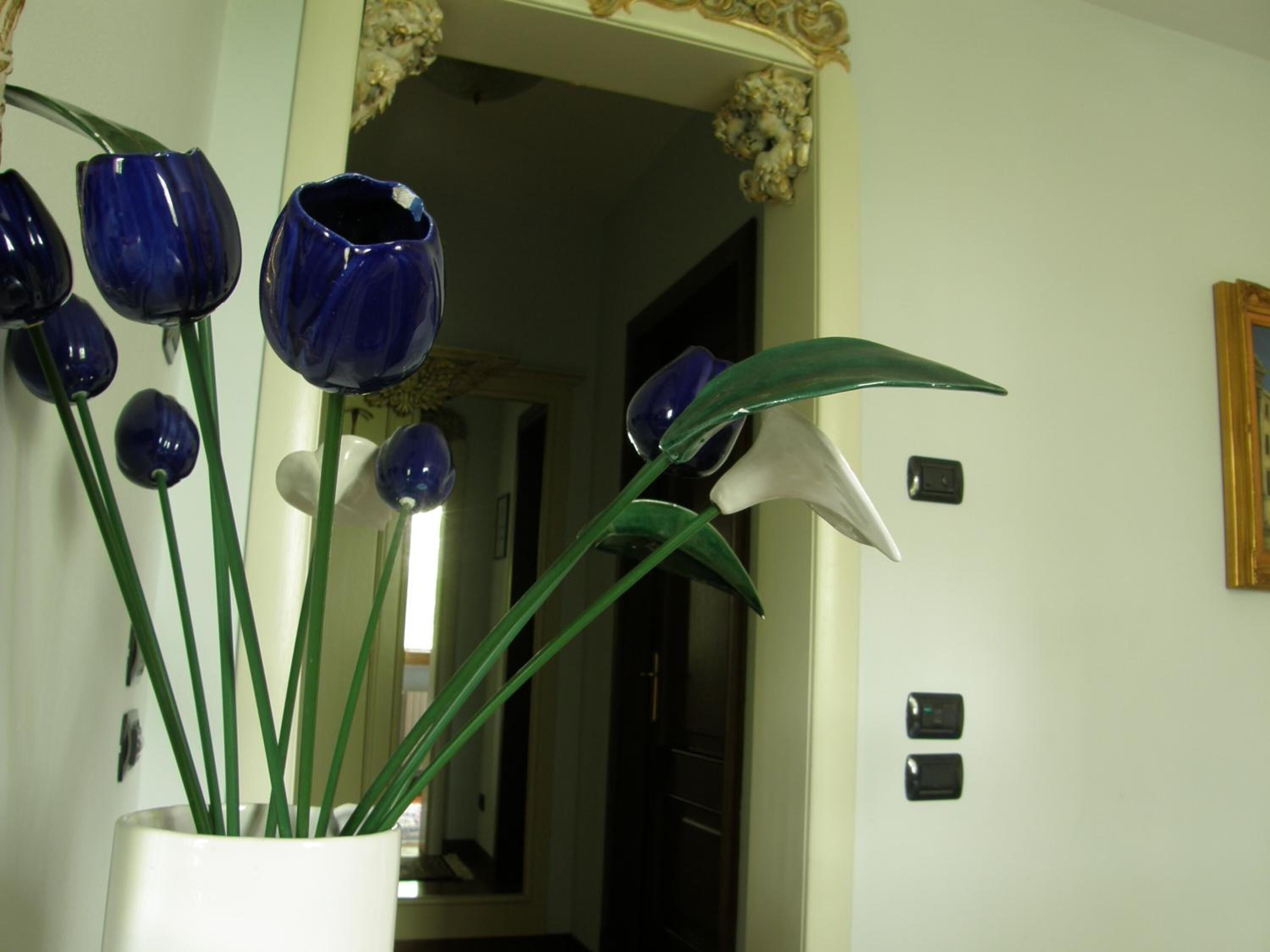 A hallway with a white vase containing green plants and blue decorative vases.
