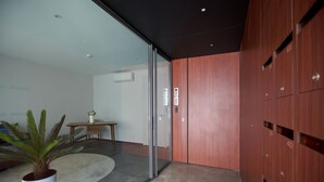 Um interior moderno com uma porta de vidro que dá para um quarto, um armário de madeira com compartimentos numerados e uma planta em vaso.