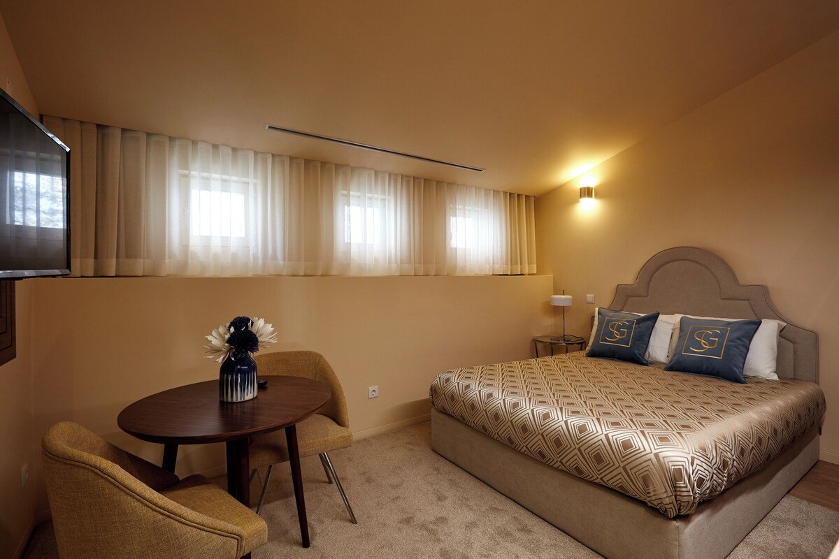 Una habitación de hotel con cama, escritorio, silla y televisor.