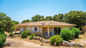 A single-story house with a tiled roof, a covered porch, and a small garden with rocks and shrubs. - Résidence Odalys San Martinu (Zonza)