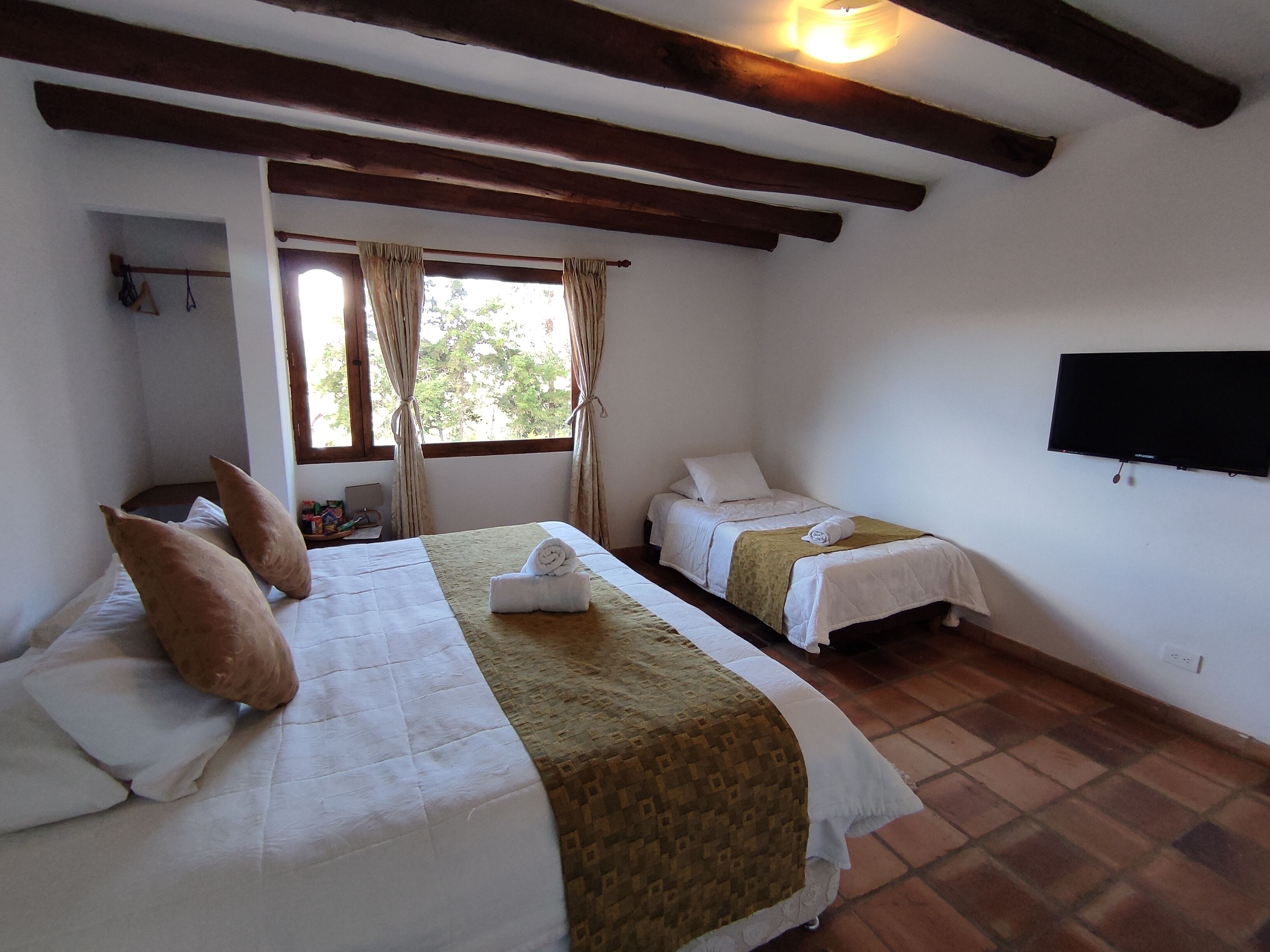 Una habitación con dos camas, un televisor de pantalla plana y una ventana con cortinas.