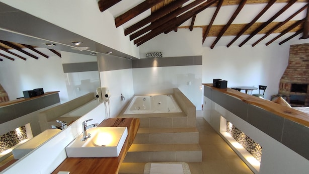 Un baño moderno con una bañera grande, dos lavamanos y un tocador de madera.