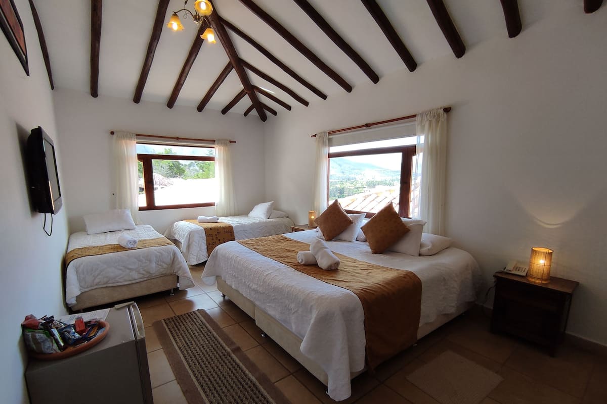 Une chambre d’hôtel avec deux lits, un petit bureau, un réfrigérateur et une vue sur l’extérieur.